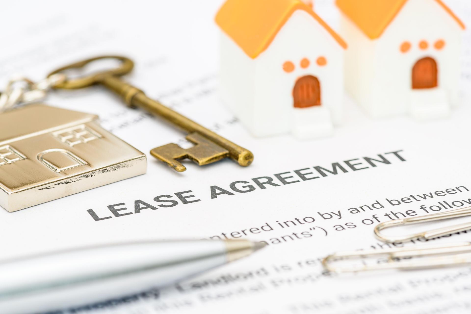 Key elements of a lease agreement and property management. House models, a key, and a pen on a lease agreement, depicting the critical steps and details involved in property leasing, legal agreements.