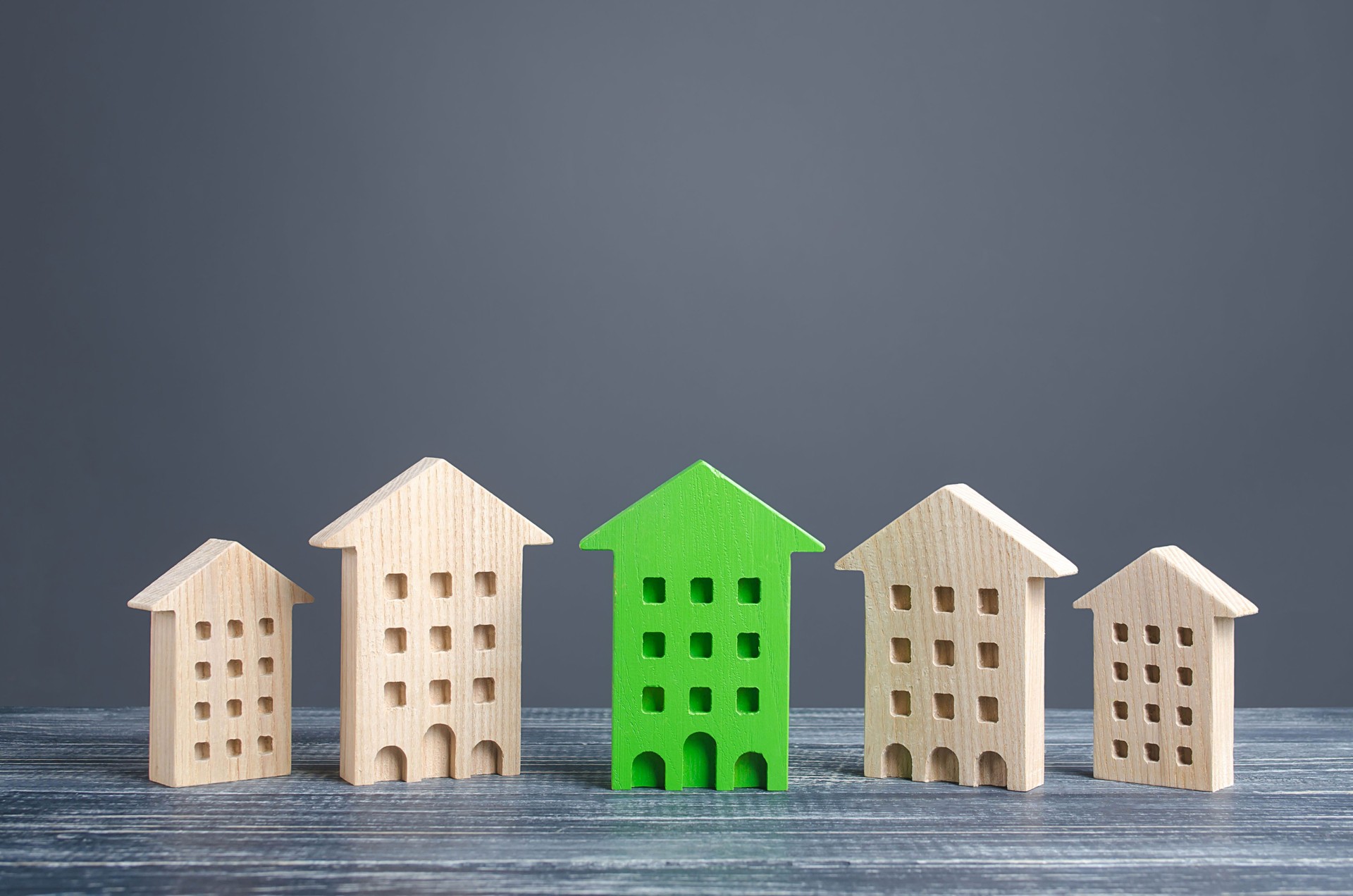 Green figure of a residential building stands out among rest of houses. Zero carbon emissions conservation energy saving technologies. Search best option apartment. High quality, convenient location.